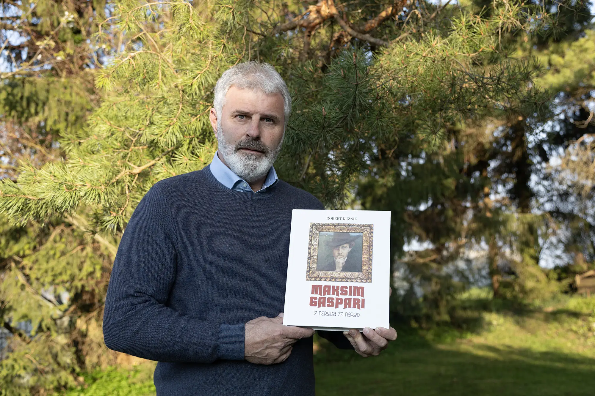 Robert Kužnik, avtor monografije Maksim Gaspari: Iz naroda za narod, s knjigo v rokah
